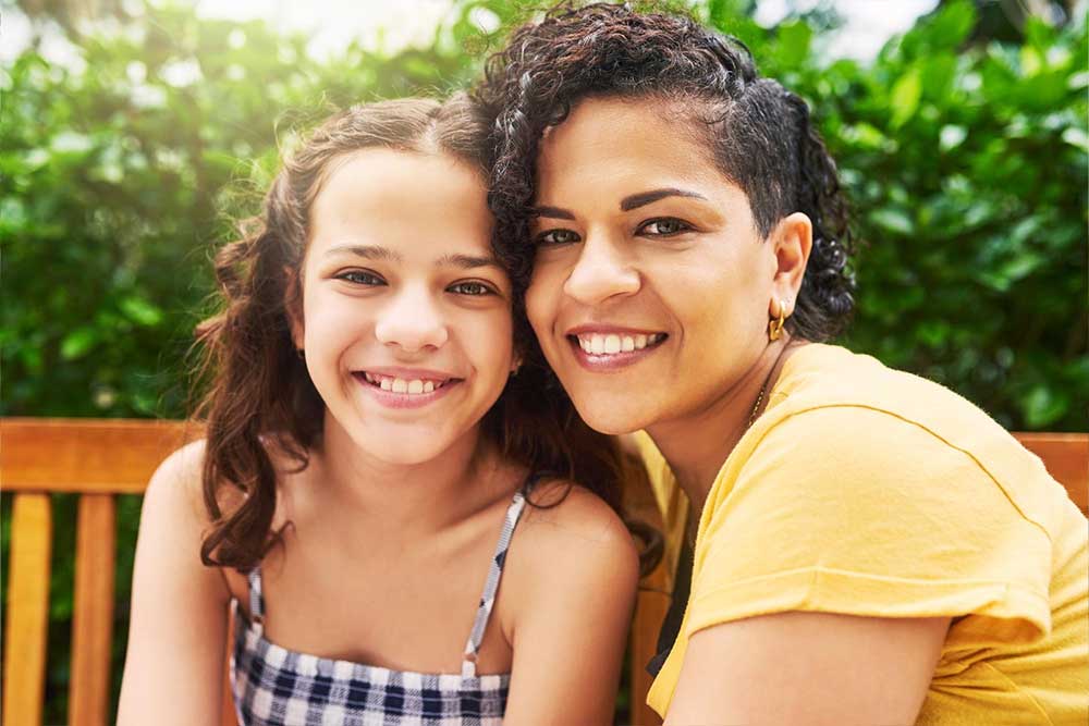 A mother and daughter smiling on a bench